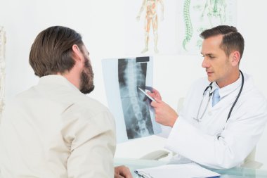 Male doctor explaining spine x-ray to patient