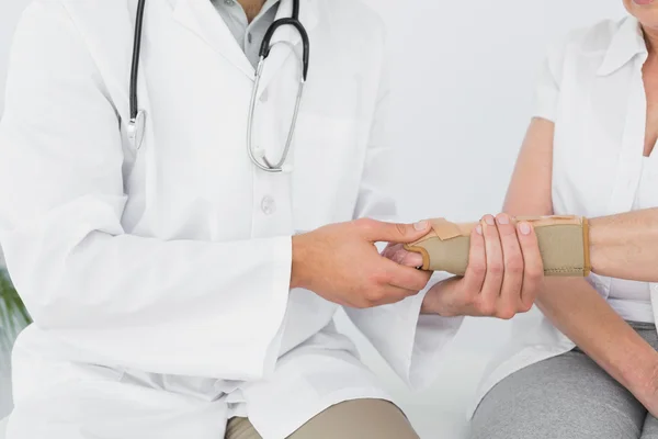 Mid section of a physiotherapist examining a woman's wrist — Stock Photo, Image