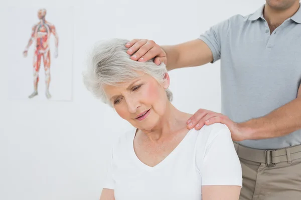 Senior vrouw de nek aanpassing gedaan krijgen — Stockfoto