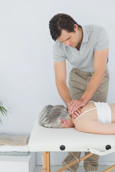 Fisioterapeuta masculino masajeando la espalda de una mujer mayor — Foto de Stock