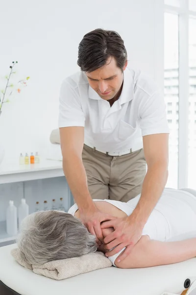 Sjukgymnast massera en äldre kvinnas axel — Stockfoto