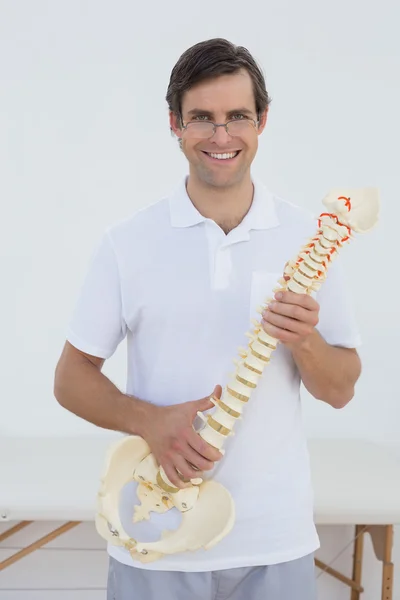 Retrato de un médico sonriente sosteniendo un modelo de esqueleto — Foto de Stock