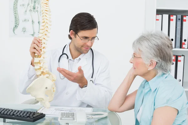 向一位高龄患者解释脊柱的男医生 — 图库照片
