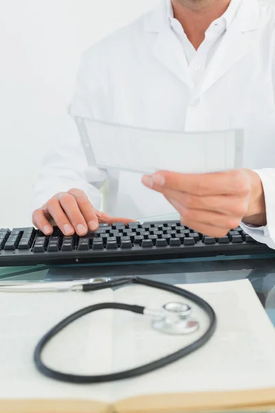 Doctor reading a note at desk in medical office — Stock Photo, Image