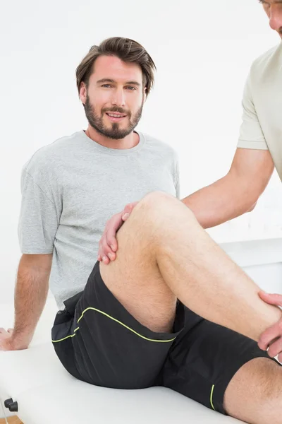 Retrato de un joven examinándose la rodilla — Foto de Stock