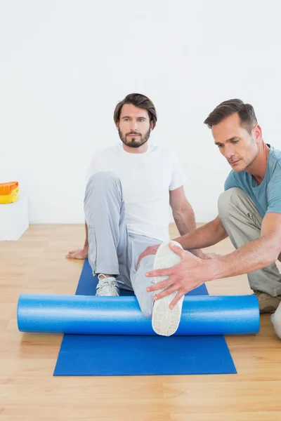 Fizyczny terapeuta badając młody mężczyzna noga — Zdjęcie stockowe