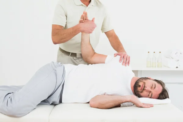 Fisioterapeuta masculino examinando a mão de um jovem — Fotografia de Stock