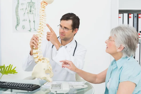 Médecin homme expliquant la colonne vertébrale à un patient âgé — Photo