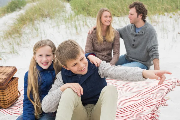 Lycklig familj av fyra på en strand picknick — Stockfoto