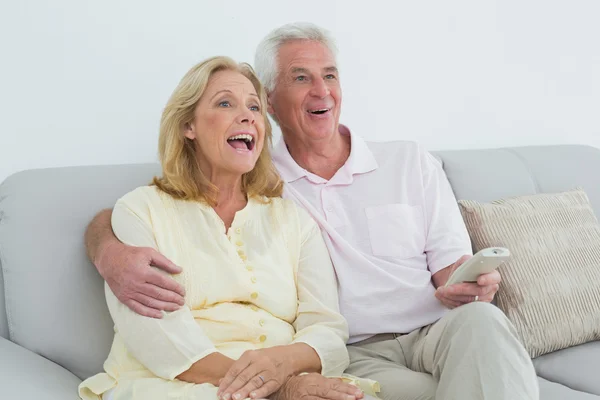 Cheerful senior couple with remote control at home — Stock Photo, Image