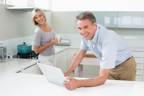 Homem e mulher felizes com laptop na cozinha — Fotografia de Stock