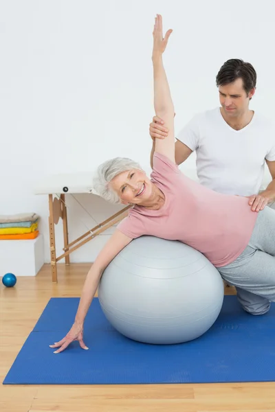 Fiziksel terapist yardımcı kadın kıdemli yoga topu ile — Stok fotoğraf