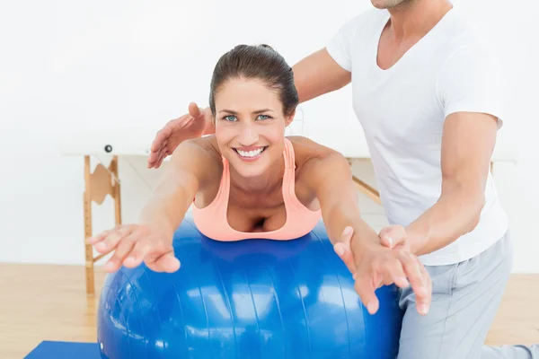 Physical therapist assisting woman with yoga ball — Stock Photo, Image