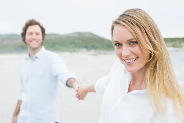 Lächelndes Paar hält Händchen am Strand — Stockfoto