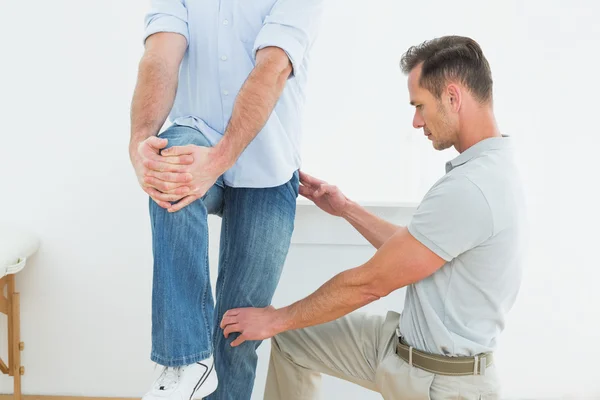 Therapist assisting young man with stretching exercises — Stock Photo, Image