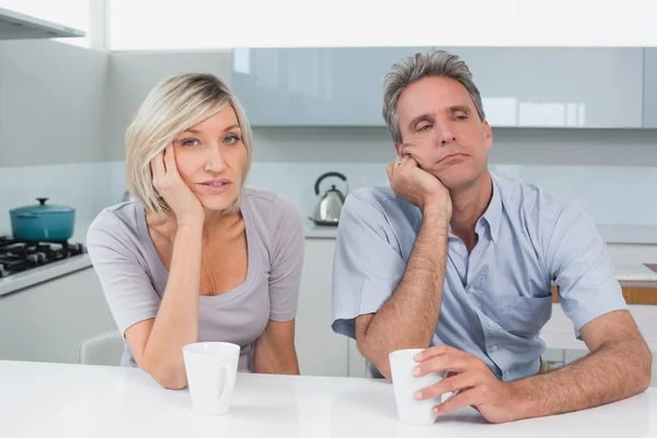 Bored couple sitting with coffee cups in kitchen — Stock Photo, Image