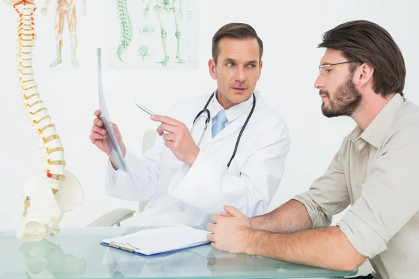 Médico masculino que explica a radiografia da coluna vertebral ao paciente — Fotografia de Stock