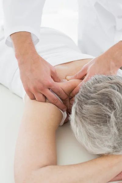 Fisioterapeuta masajeando la espalda de una mujer mayor — Foto de Stock