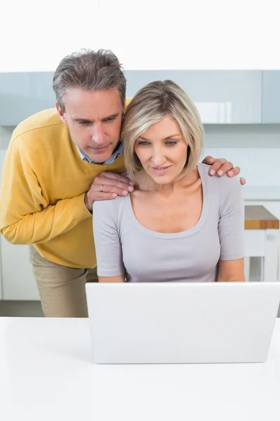 Paar kijken laptop in de keuken — Stockfoto