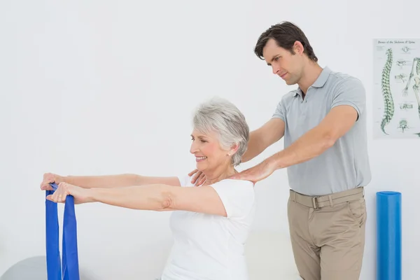 Terapeuta masculino que ayuda a la mujer mayor con ejercicios — Foto de Stock