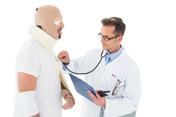 Médico auscultando paciente atado en vendaje con estetoscopio —  Fotos de Stock