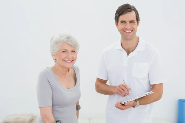 Terapeuta masculino sonriente y paciente mayor discapacitado — Foto de Stock