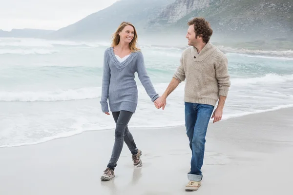 Paar hält Händchen und geht am Strand spazieren — Stockfoto