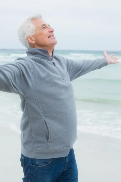 Äldre man med armarna utsträckta på stranden — Stockfoto