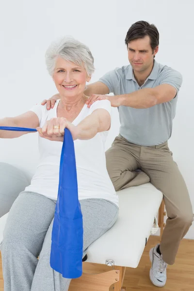 Мужской терапевт помогает пожилой женщине с упражнениями — стоковое фото