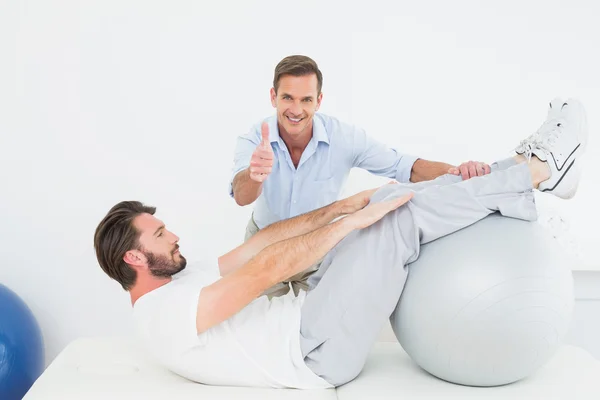 Therapist gestures thumbs up while assisting man do sit ups — Stock Photo, Image