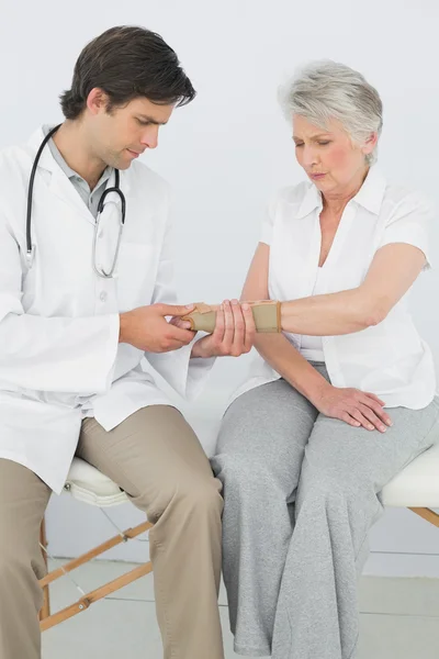 Male physiotherapist examining a senior woman's wrist — Stock Photo, Image