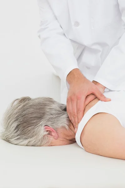 Fisioterapeuta masajeando la espalda de una mujer mayor — Foto de Stock