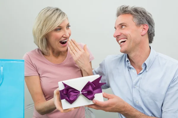 Man giving a surprised woman a birthday gift — Stock Photo, Image