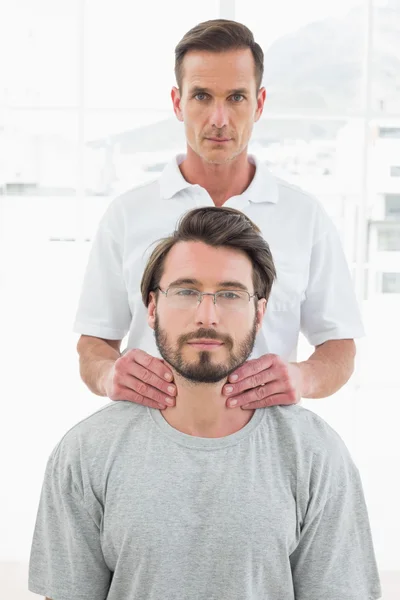 Terapista maschile massaggiando il collo di un giovane — Foto Stock