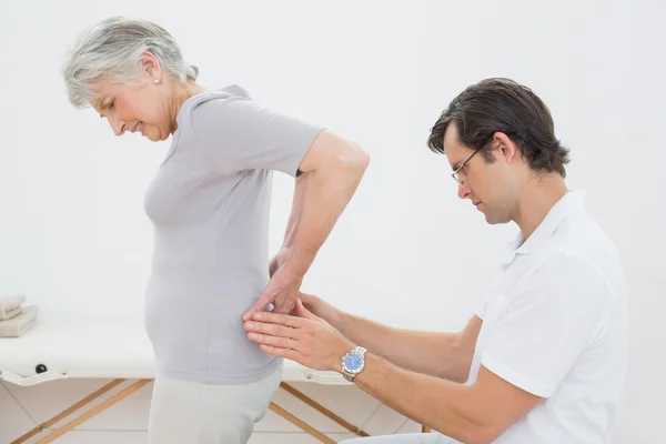 Fisioterapeuta examinando espalda de mujer mayor — Foto de Stock