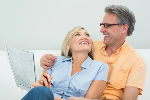 Glückliches Paar mit Zeitung im Wohnzimmer — Stockfoto
