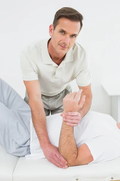 Мужской физиотерапевт осматривает руку мужчины — стоковое фото