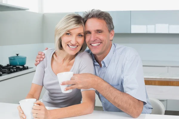 Happy loving couple with coffee cups in kitchen — Stock Photo, Image