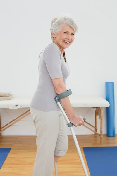 Seitenansicht einer lächelnden Seniorin mit Krücken — Stockfoto