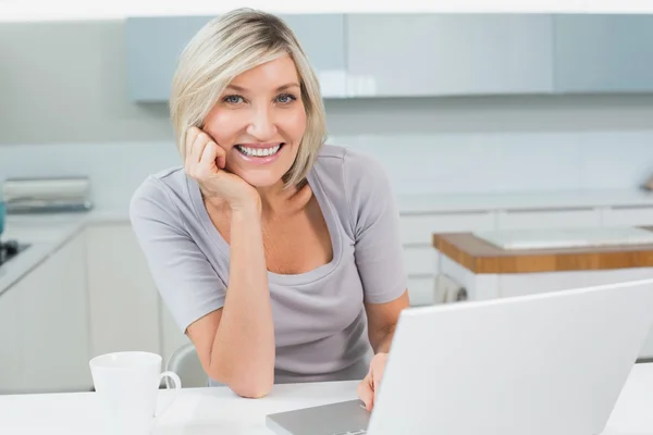 Casual woman with coffee and laptop in kitchen — Stock Photo, Image