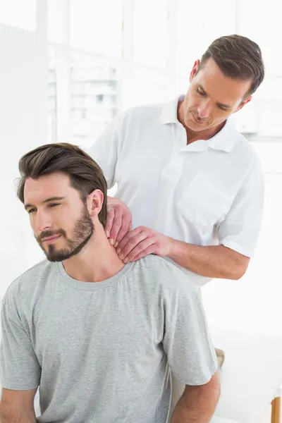 Terapeuta do sexo masculino massageando o pescoço de um jovem — Fotografia de Stock