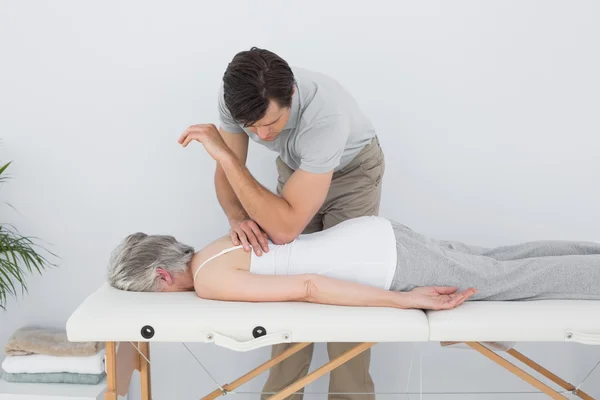 Manlig sjukgymnast massera en äldre kvinnas rygg — Stockfoto