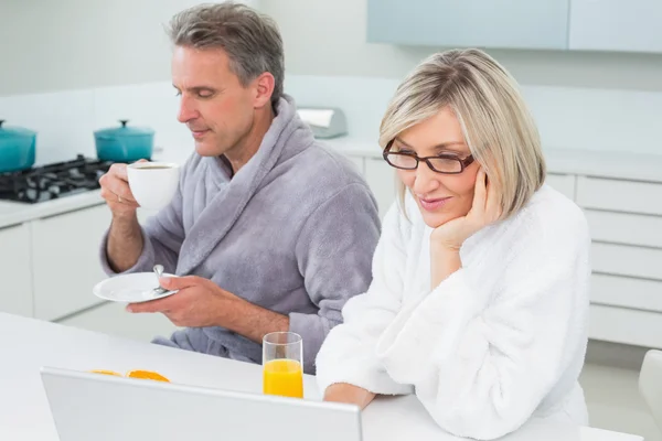 Paar in Bademänteln mit Kaffee und Saft mit Laptop — Stockfoto