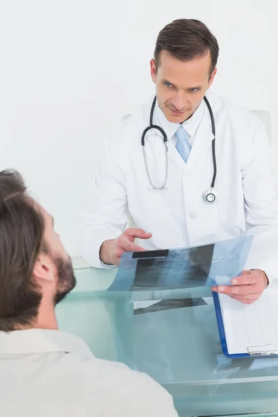 Male doctor explaining spine x-ray to patient — Stockfoto