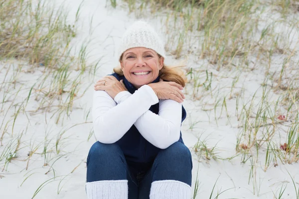 Glückliche Seniorin fühlt sich am Strand kalt — Stockfoto