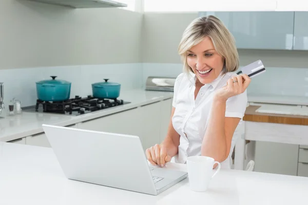 Vrolijke vrouw doen online winkelen in de keuken — Stockfoto