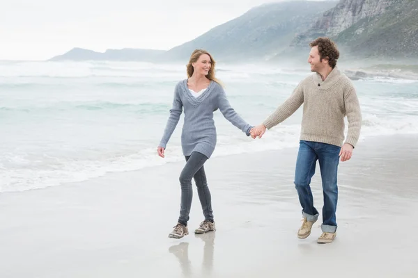 Paar hält Händchen und geht am Strand spazieren — Stockfoto