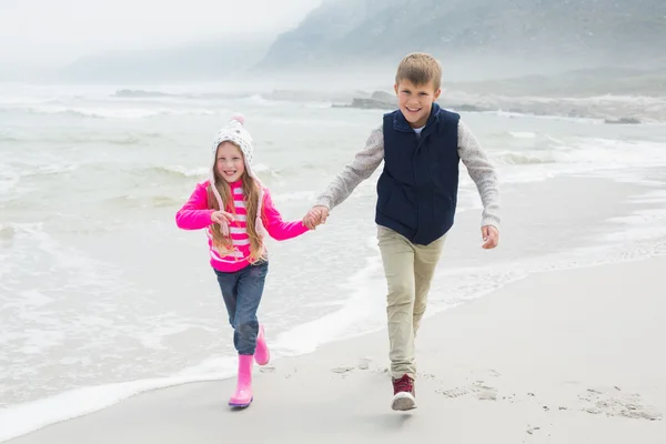 Feliz irmão e irmã andando de mãos dadas na praia — Fotografia de Stock