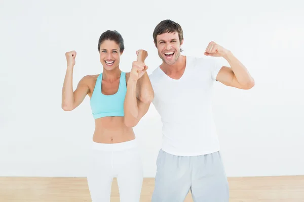 Cheerful fit couple clenching fists in fitness studio — Stock Photo, Image