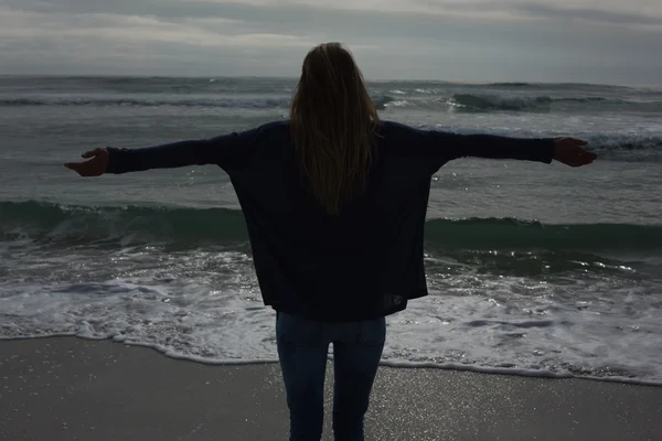 Silhouette Rückansicht einer Frau mit ausgestreckten Armen am Strand — Stockfoto